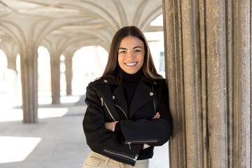 Cool woman smiling at camera standing with arms crossed outdoors