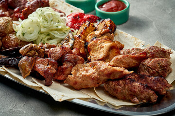Assorted Grilled pork and chicken shish kebab in a plate with sauce and pita bread. Close-up.