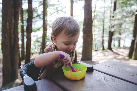 Toddler eating at picnic table while camping at Hicks Lake, Harrison Hot Springs, British Columbia, Canada