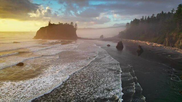 Flying over Ruby beach at sunset, Oregon, United States. Magnificent black beach in fog, cliffs and waves of the Pacific Ocean. Aerial drone shot