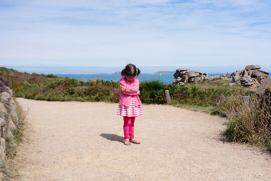 Front view of sulking young girl on beautiful summer day in Ploumanach, Brittany, France