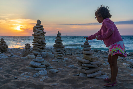 Girl stacking pebbles on beach