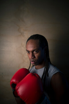 A young African American man poses in boxing gloves.
