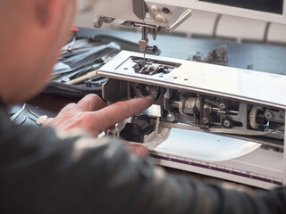 Male master repairs the sewing machine. Professional adjustment of a sewing machine in a small...