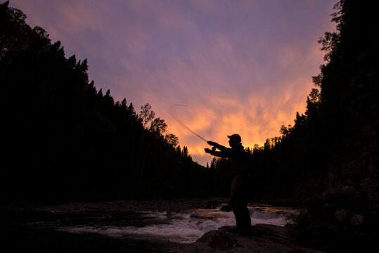 Fly fisherman casting into Le Chutes pool on York River at sunset, Gaspe, Quebec, Canada