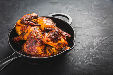 Roasted half chicken in pan on black background