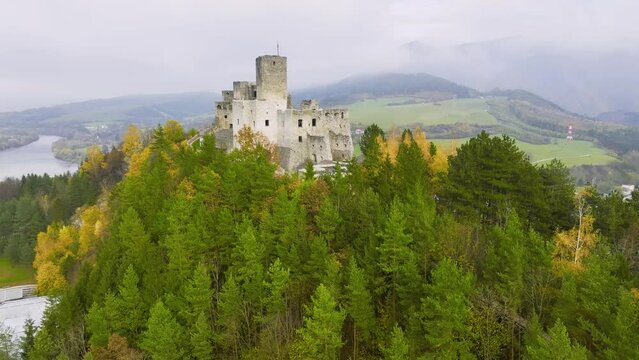 Slovak castles: aerial view of Strečno castle, towering on a cliff above the Váh river valley. Autumn, colourful leaves, mists in the valley, the castle above the hilly landscape. 
