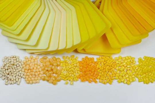 different yellow plastic polymer resin granulates with color samples plates in laboratory