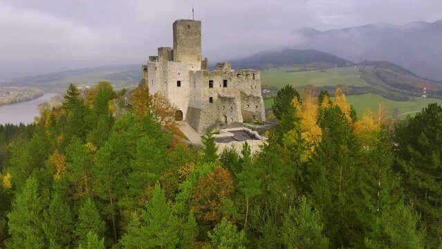 Slovak castles: aerial view of Strečno castle, towering on a cliff above the Váh river valley. Autumn, colourful leaves, mists in the valley, the castle above the hilly landscape.  Slovakia.