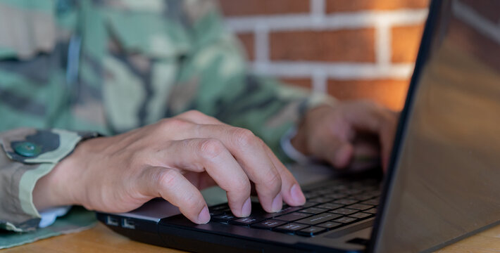 close up soldier man hand typing on keyboard laptop to check and use command for military operation test system in office room concept
