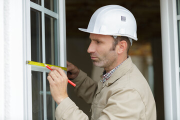 a male worker measuring a window