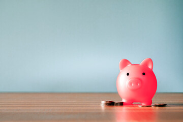 Piggy Bank and a few coins on gray background. The concept of saving less saving money piggy bank...