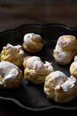Decorating profiteroles with powdered sugar. Eclairs with icing sugar