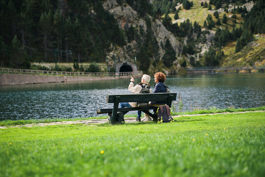 Pareja de abuelos sentados en un banco, contemplando la vista al lago.