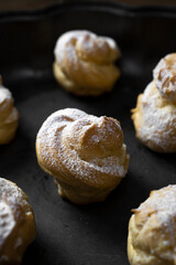 Decorating profiteroles with powdered sugar. Eclairs with icing sugar