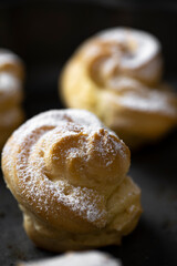 Decorating profiteroles with powdered sugar. Eclairs with icing sugar