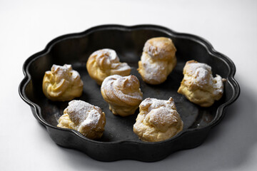 Decorating profiteroles with powdered sugar. Eclairs with icing sugar