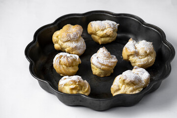 Decorating profiteroles with powdered sugar. Eclairs with icing sugar