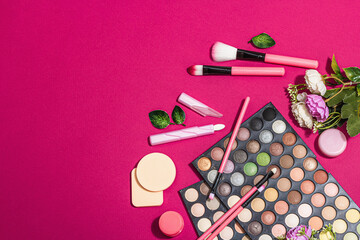 Make up set with colorful eyeshadow palettes, brushes, sponges and flowers. Viva magenta background