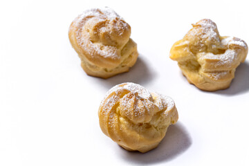 Decorating profiteroles with powdered sugar. Eclairs with icing sugar
