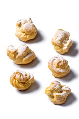 Decorating profiteroles with powdered sugar. Eclairs with icing sugar