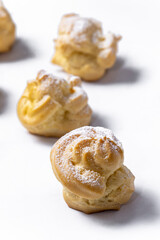 Decorating profiteroles with powdered sugar. Eclairs with icing sugar