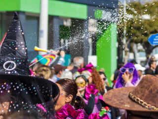 Blurred view of carnival parade on the street with unrecognizable people in costumes and artificial...