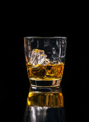 Whisky glass with ice on black background