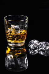 Whisky glass with ice on black background