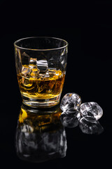 Whisky glass with ice on black background