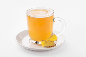 Hot ginger drink with spices in a transparent cup on a white background.