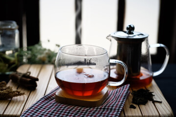 Herbal hot tea drink in glass with steam in festive composition on table