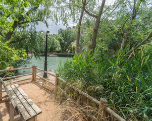 Bench in the recreational area of Alcala del Jucar, overlooking the green and dense vegetation of the Jucar river.