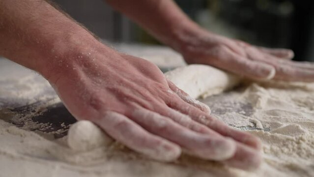 Rolling out dough close-up. A man rolls the dough on a wooden table with a wooden rolling pin.