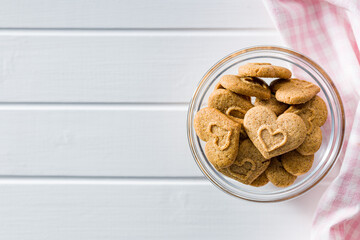 Sweet gingerbread hearts in bowl on white table. Top view.