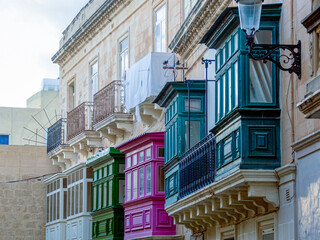 Obraz premium Fragment of the building's facade with traditional wooden ornate balconies painted in Valletta, Malta.