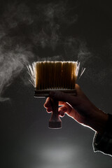 male hand holds vintage yellow talcum brush. Classic wide neck duster with wooden handle.