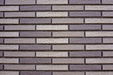 Texture of narrow clean beige gray bricks. Background of a modern house wall.