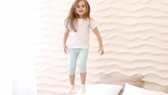 A small child happily jumps in bed