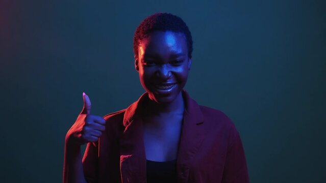 Like gesture. Yeah approval. Perfect choice. Red blue neon color light satisfied happy woman recommending with thumb up isolated on dark night gif loop boomerang animation.