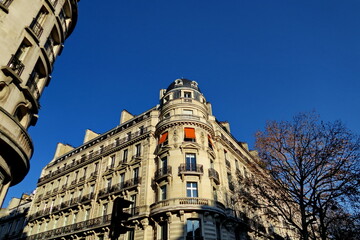 Fototapeta na wymiar Immeuble arrondi ancien avec balcons. Store coloré. Ciel bleu.