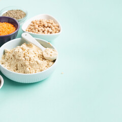 Healthy Dry Pea Protein Powder and Plant Based Protein Food (legumes, lentils, beans, seeds) on Blue Green Background.