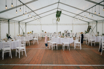 gedeckte Tische unter einem Zelt auf einer Hochzeit