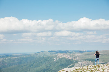 Fototapeta na wymiar a woman standing on top of a mountain above a blue sky on a hike trip
