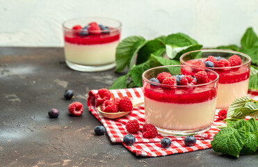 Delicious italian dessert panna cotta with berry sauce on a dark background in small jars. place for text
