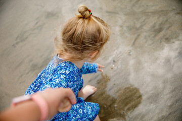 Little cute toddler girl at the Ballybunion surfer beach, having fun on with playing on west coast of Ireland. Happy child enjoying Irish summer and sunny day with family.