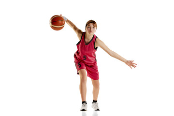 Portrait of teen girl, basketball player in uniform with ball, in motion, training isolated over white studio background. Concept of sportive lifestyle, active hobby, health, endurance, competition