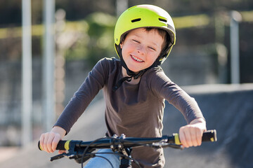 adorable boy rides bike and wears protective helmet