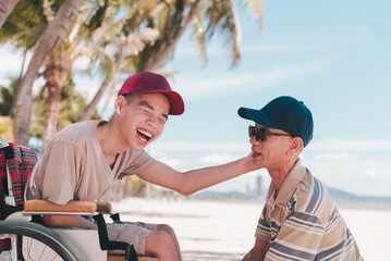 Young man with disability on wheelchair and father or volunteer or caregiver at happy time on the beach with Family Caregiving, Travel and vacation in summer, Positive photos, mental health concept.