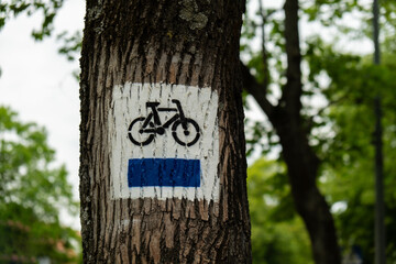 Bicycle route sign on tree in the forest. Blue path cycling road sign in the woods on trunk. The blue trail. Marking the tourist trail